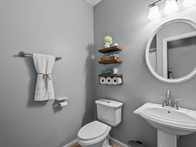 bathroom with a sink, baseboards, and toilet