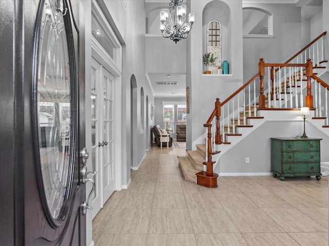 tiled foyer entrance with stairway, a notable chandelier, baseboards, and a towering ceiling