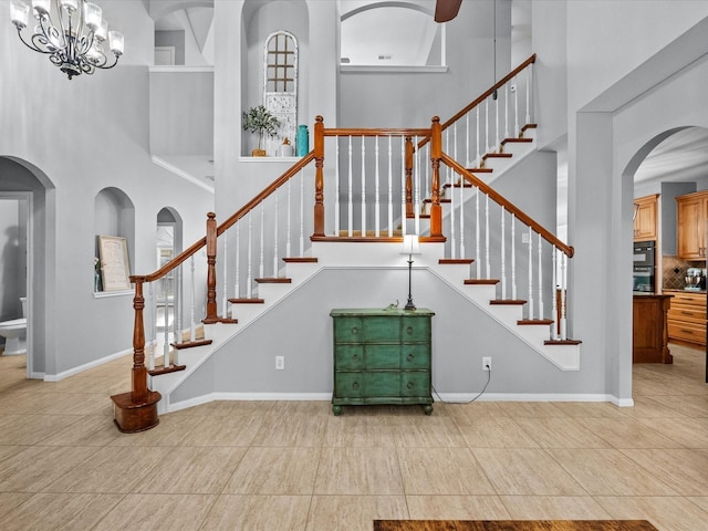 stairs with tile patterned floors, baseboards, and a towering ceiling