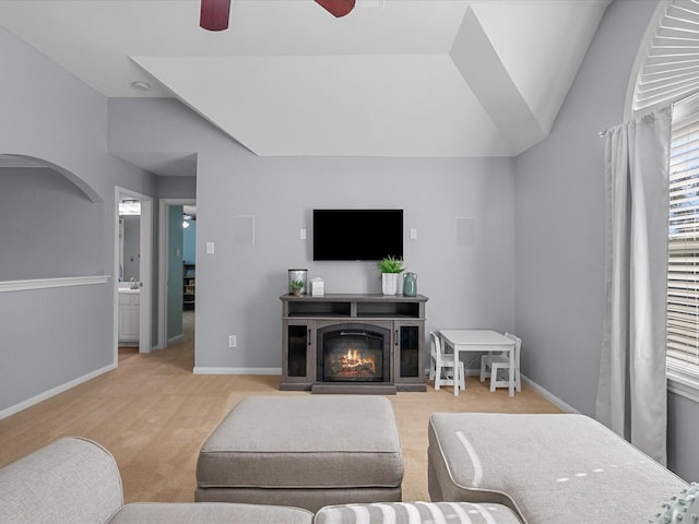 living room featuring vaulted ceiling, light carpet, baseboards, and ceiling fan