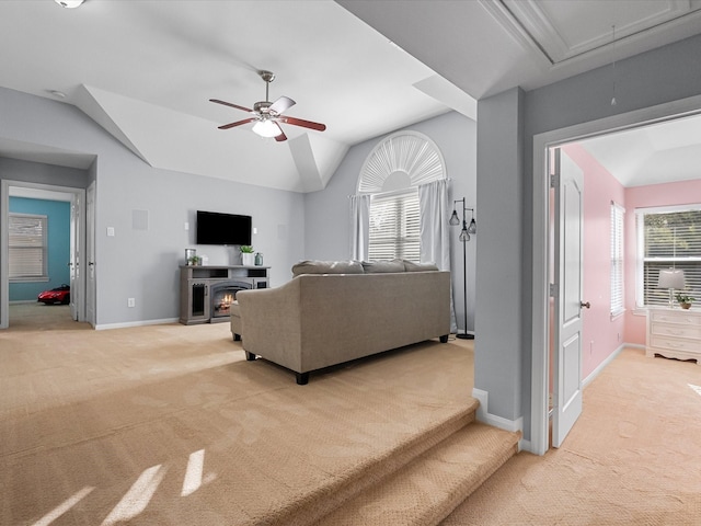 living room featuring a ceiling fan, baseboards, attic access, vaulted ceiling, and light colored carpet