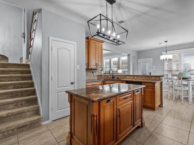 kitchen with a chandelier, decorative backsplash, a kitchen island, and brown cabinetry