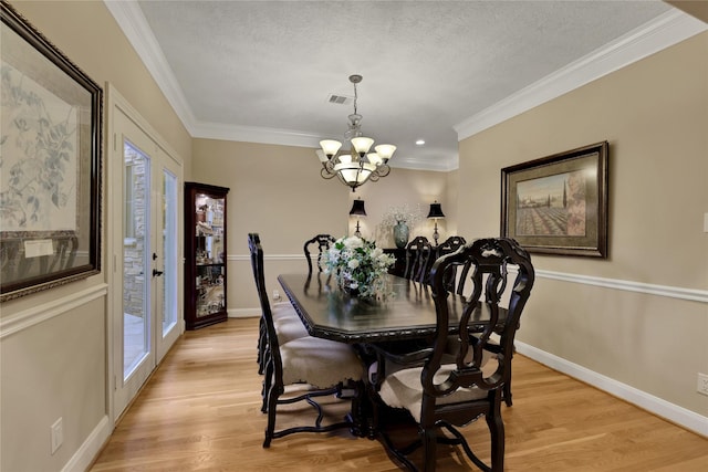 2814 S Cotswold Manor Dr, Kingwood, TX 77339 - dining space with baseboards, light wood-style floors, a textured ceiling, crown molding, and a chandelier