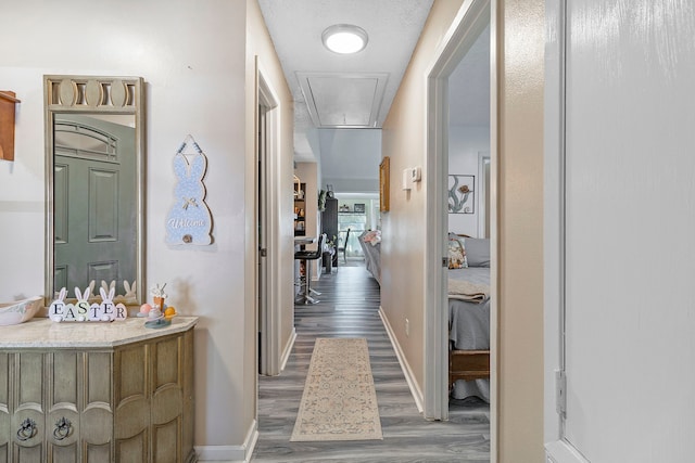 hall with attic access, wood finished floors, and baseboards