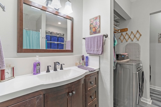 bathroom featuring wood finished floors, vanity, washer / clothes dryer, and curtained shower