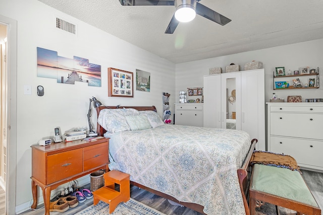 bedroom with wood finished floors, visible vents, and ceiling fan