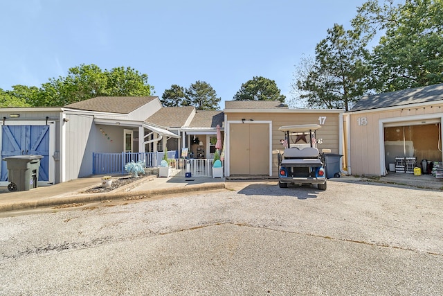 view of front of home featuring covered porch, driveway, and roof with shingles