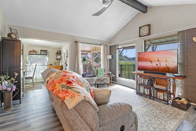 living room with wood finished floors, a ceiling fan, a textured ceiling, and lofted ceiling with beams