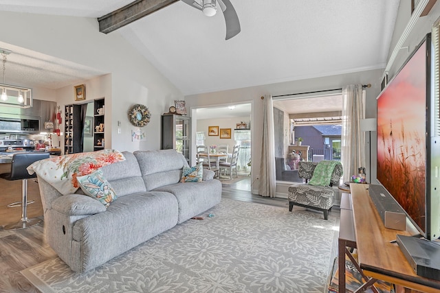 living room with wood finished floors, ceiling fan, and vaulted ceiling with beams