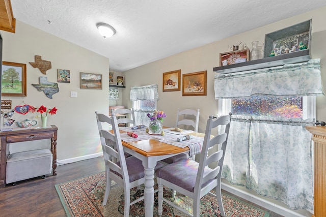 dining space with a textured ceiling, vaulted ceiling, wood finished floors, and baseboards