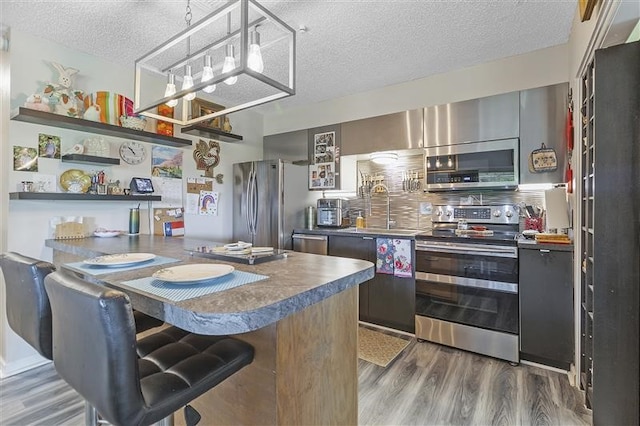 kitchen featuring wood finished floors, appliances with stainless steel finishes, a kitchen bar, and a sink