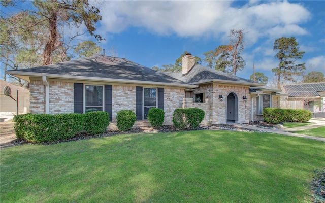 view of front of house featuring a front yard, brick siding, and a chimney