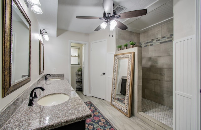 bathroom with a ceiling fan, a walk in shower, a sink, wood finished floors, and double vanity