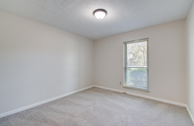 carpeted spare room featuring baseboards and a textured ceiling