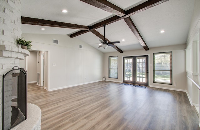 unfurnished living room with visible vents, a ceiling fan, lofted ceiling with beams, and light wood-style floors