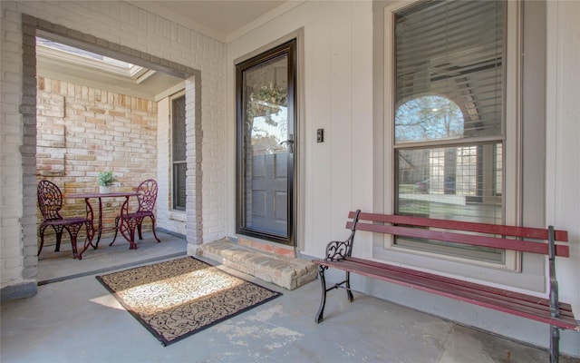 view of exterior entry featuring brick siding, a patio area, and outdoor dining area