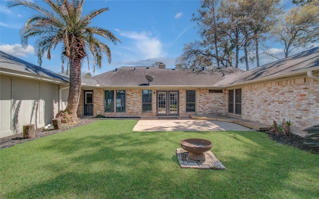 rear view of house featuring a patio, a yard, a fire pit, french doors, and brick siding