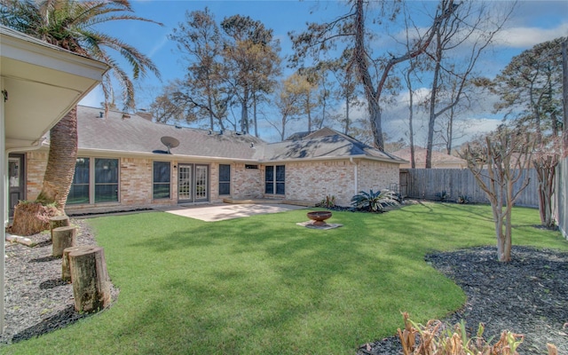 back of house featuring brick siding, a patio, fence, and a lawn