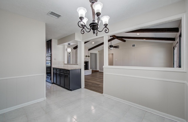 kitchen featuring visible vents, a wainscoted wall, lofted ceiling with beams, ceiling fan with notable chandelier, and hanging light fixtures