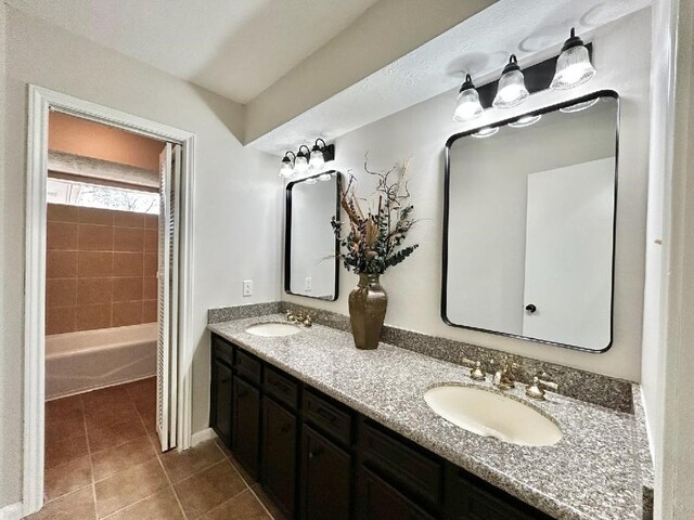 bathroom featuring tile patterned floors, double vanity, a tub to relax in, and a sink