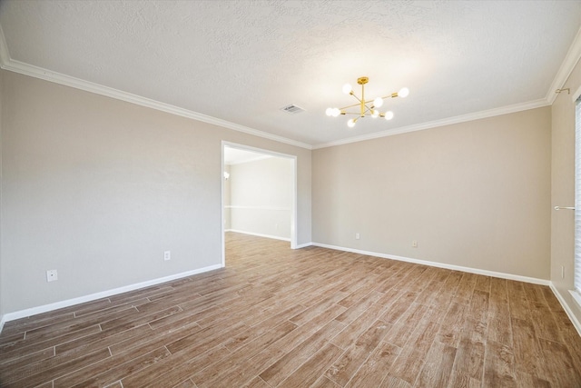 spare room featuring wood finished floors, baseboards, visible vents, a textured ceiling, and a notable chandelier