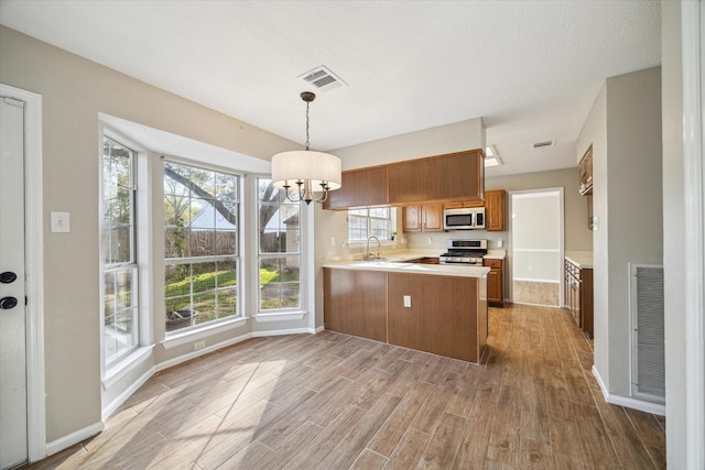 kitchen featuring a peninsula, light wood finished floors, visible vents, and appliances with stainless steel finishes