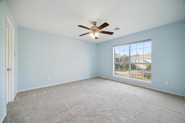 carpeted spare room with visible vents, baseboards, and a ceiling fan