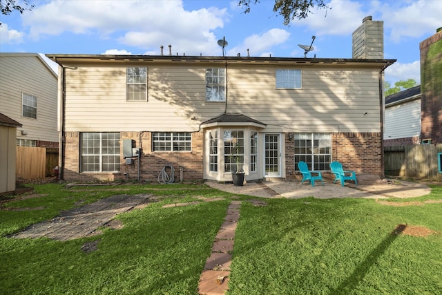 rear view of house with brick siding, a lawn, a patio, and fence