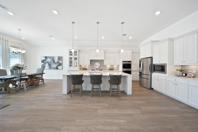 kitchen with a kitchen breakfast bar, backsplash, stainless steel appliances, white cabinets, and light countertops