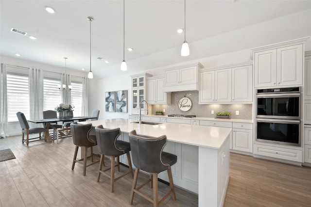 kitchen featuring visible vents, a sink, stainless steel appliances, light countertops, and decorative backsplash