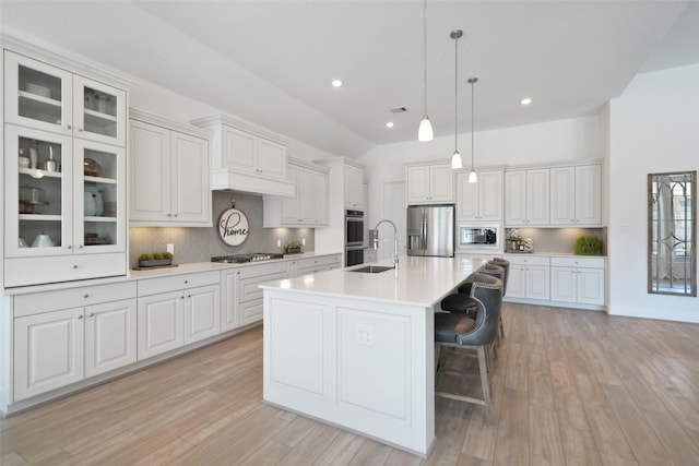 kitchen featuring light wood-type flooring, an island with sink, a sink, stainless steel appliances, and light countertops