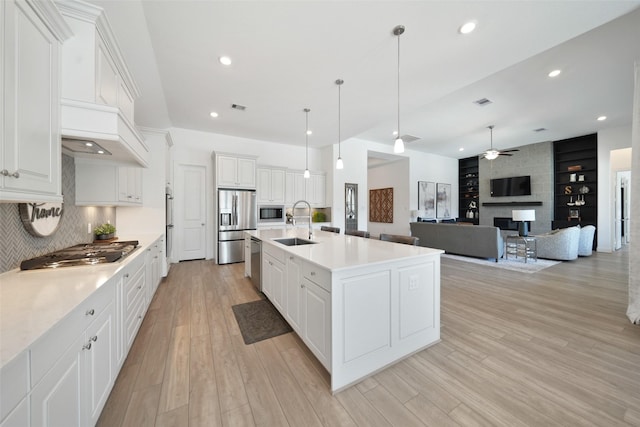 kitchen featuring light wood-type flooring, a sink, appliances with stainless steel finishes, light countertops, and ceiling fan