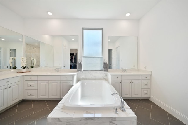 bathroom featuring a sink, baseboards, a bath, and tile patterned floors