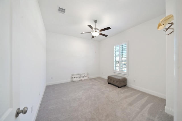 carpeted spare room with visible vents, baseboards, and a ceiling fan