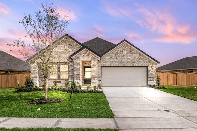 french country inspired facade with concrete driveway, fence, a lawn, and a garage