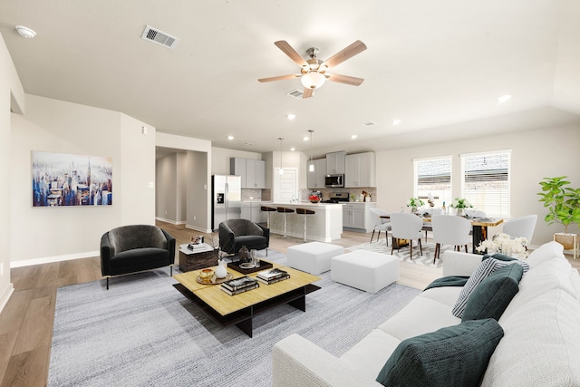 living area with ceiling fan, recessed lighting, visible vents, and light wood-type flooring