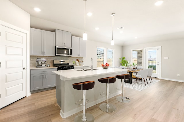 kitchen featuring light wood finished floors, plenty of natural light, tasteful backsplash, stainless steel appliances, and light countertops