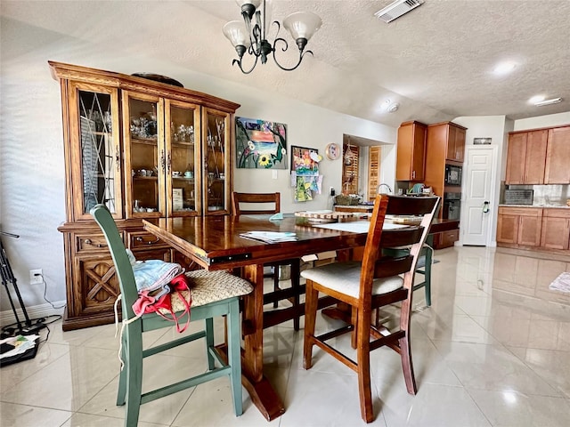 dining area featuring a notable chandelier, visible vents, light tile patterned floors, and a textured ceiling