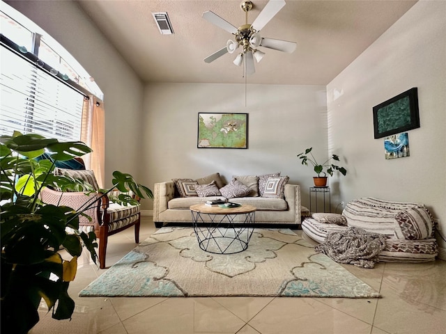 tiled living room featuring visible vents, a textured ceiling, and a ceiling fan