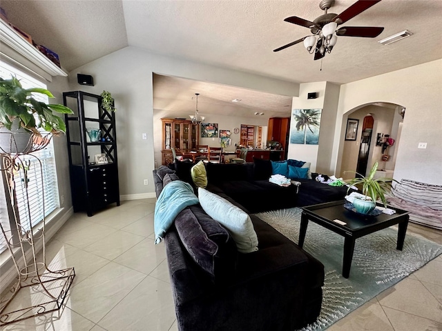 living room featuring visible vents, vaulted ceiling, light tile patterned flooring, arched walkways, and a ceiling fan