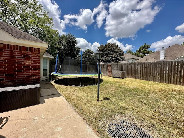 view of yard with a patio area, a trampoline, and fence