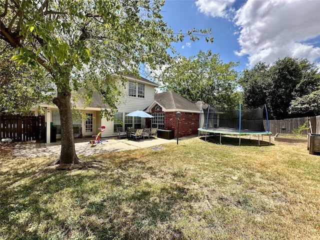 view of yard featuring a trampoline, a patio area, and fence