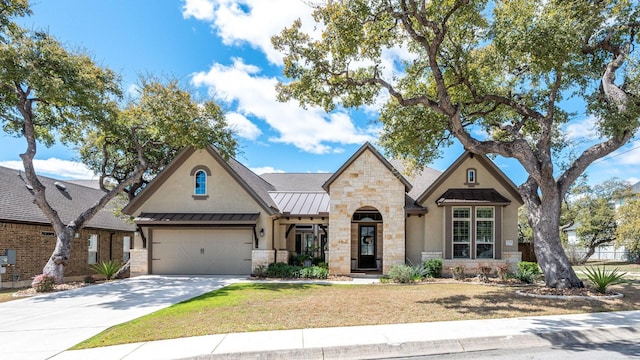 view of front of house with stucco siding, a standing seam roof, stone siding, concrete driveway, and metal roof