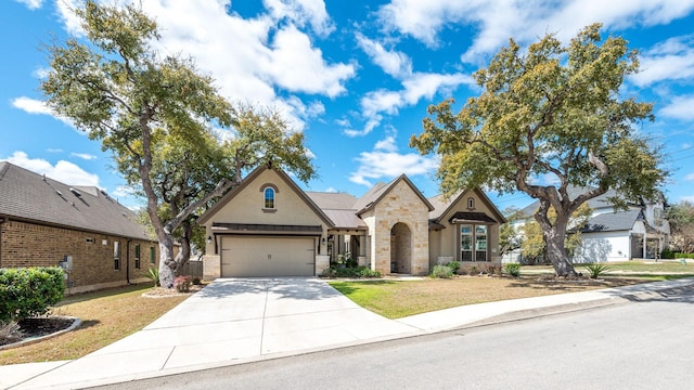 french country style house with stone siding, an attached garage, driveway, and a front yard