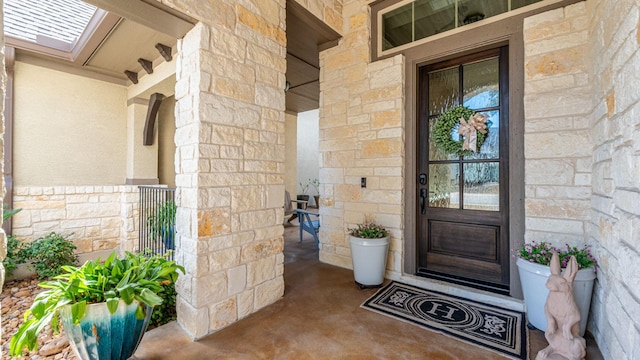 view of exterior entry featuring stone siding and covered porch