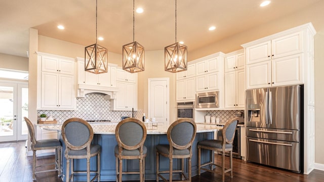 kitchen with stainless steel appliances, dark wood-type flooring, an island with sink, and white cabinets