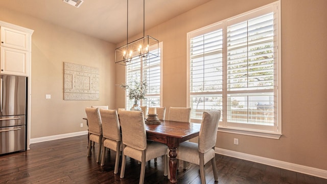 dining space with dark wood finished floors, a notable chandelier, visible vents, and baseboards