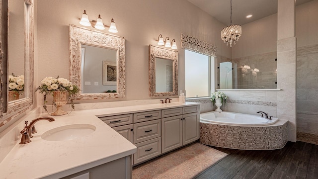 full bathroom with a garden tub, wood finished floors, double vanity, and a sink