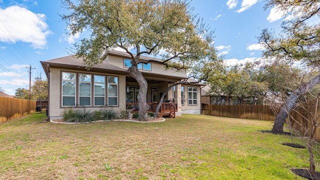 back of house featuring a yard, a fenced backyard, and stucco siding