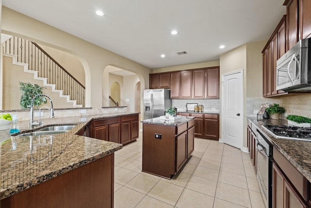 kitchen with visible vents, a sink, tasteful backsplash, a kitchen island, and appliances with stainless steel finishes